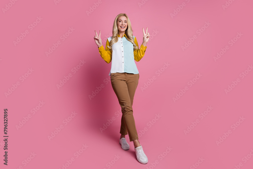 Poster full size portrait of stunning positive girl arms fingers show v-sign empty space isolated on pink c