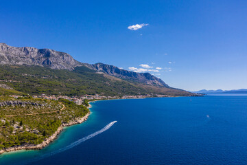 A small boat with tourists slowly floats on clear water. Amazing coastline. Aerial photography. The...