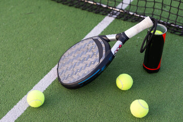 Blue padel racket and yellow balls placed on court near net on sunny day - 796332828