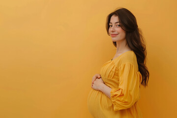 Obraz premium Pregnant woman in yellow dress against yellow background. Expectant mother carefully holds her tummy with hands