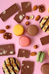 Pastel macarons, almond chocolate, peanut butter cookies and various nuts on bright pink background. Top view.