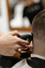 Barber uses clipper on mans hair, near forehead, ear, chin, temple