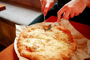 Hand of woman cutting langos at restaurant. Female hands cutting langos with fork and knife