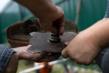 Close-up of tightening the nut on the metal disc on a grass trimmer. In order to mow tall, dense...