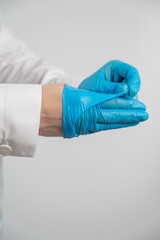 Doctor takes off latex gloves on a white background. Vertical photo. 