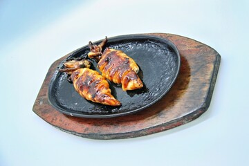 Grilled squids or 'Cumi Bakar' is a sweet and tangy seafood dish that is often sold as street food in Indonesia. It is marinated in sweet soy sauce and a mixture of spices before being grilled. 