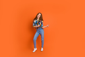 Photo of cheerful lovely girl wear stylish print clothes dance good mood isolated on vibrant orange color background
