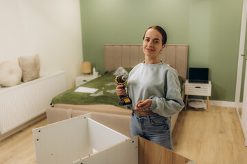 Beautiful young happy woman assembling furniture at home