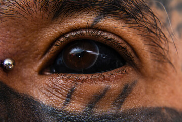 Closeup of a man with face tattoos showing off his black eye tattoos. A Blackened sclera. Scleral...