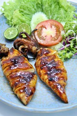 Grilled squids or 'Cumi Bakar' is a sweet and tangy seafood dish that is often sold as street food in Indonesia. It is marinated in sweet soy sauce and a mixture of spices before being grilled. 