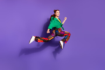 Full size photo of optimistic woman dressed vintage pants green shirt running on sale to empty space isolated on purple color background