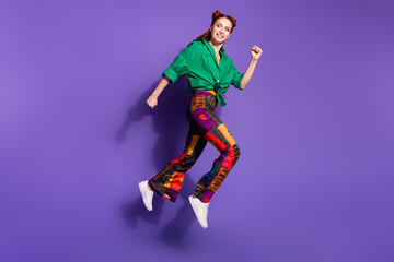 Fototapeta na wymiar Full size photo of girlish cheerful woman dressed vintage pants running look at promotion empty space isolated on purple color background