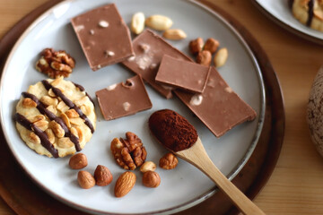 Cup of tea or coffee, cookies, macaroons, chocolate, various nuts and cocoa powder on wooden table. Selective focus.