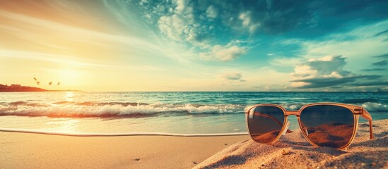 Fototapeta na wymiar sunglasses on beach sand during sunset