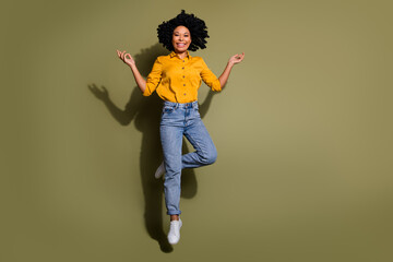 Full size photo of nice young woman jump empty space wear yellow shirt isolated on khaki color...