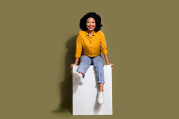 Full size photo of nice young woman sit podium wear yellow shirt isolated on khaki color background
