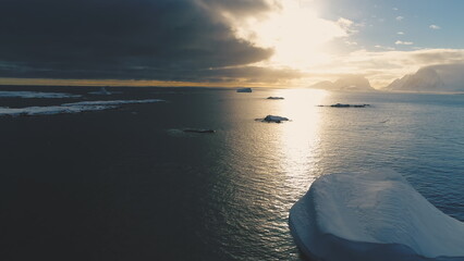 Iceberg in sunset above Antarctica. Front aerial view. Sun reflection on ocean water in Antarctic...