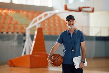 Happy coach with  basketball looking at camera.