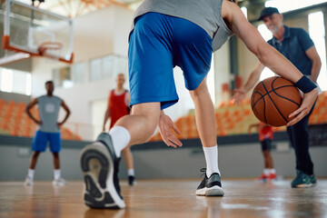 Close up of athlete playing basketball at indoor court.