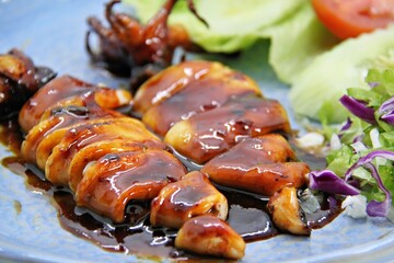 Grilled squids or 'Cumi Bakar' is a sweet and tangy seafood dish that is often sold as street food in Indonesia. It is marinated in sweet soy sauce and a mixture of spices before being grilled. 