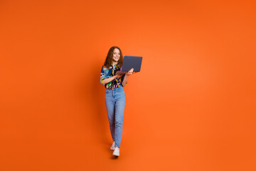 Photo of cheerful lovely nice girl wear stylish clothes reading sms going isolated on vivid orange color background
