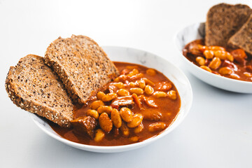 plant-based homemaed baked beans with butter beans and tempeh cubes in spicy tomato sauce served with grain bread