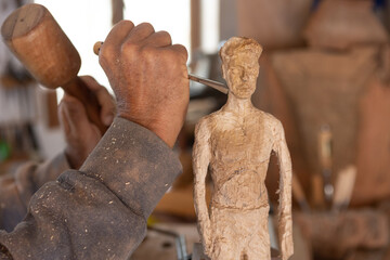 artisan wood carving male figure sculpture artist in workshop 