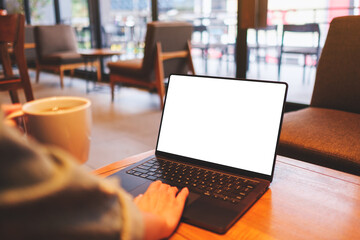 Mockup image of a woman using and working on laptop computer with blank white desktop screen while drinking coffee in cafe - 796411457