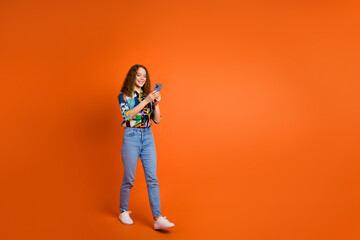Photo of lovely cheerful girl dressed trendy clothes typing texting going empty space isolated on orange color background