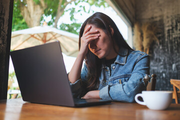 A woman get headache and stressed while working online on laptop computer at home - 796412084