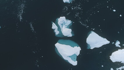 White and blue Iceberg top down aerial drone view. Antarctica flight. Overview the lone snow white ice mountain, among polar winter ocean water. Beauty of wild untouched nature. .