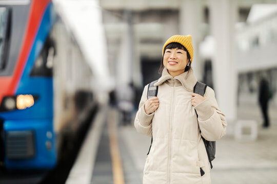 A japanese passenger is standing at platform on railway station and waiting for a train.
