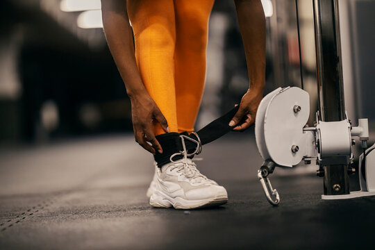 Close up of a black sportswoman's hands adjusting dual pulley machine for exercise at gym.