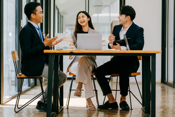 Young motivated Asian business team discussing oh business strategy in the modern meeting room.