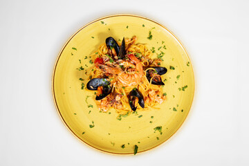 Seafood risotto, a typical Italian dish also called risotto alla pescatora. Rice in a yellow plate with mussels, prawns, cuttlefish and tomato.