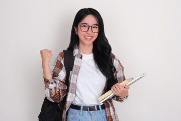 Female college student holding books and carrying backpack showing excited expression