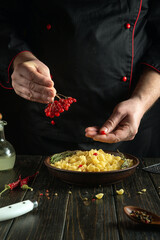 Cooking pasta with viburnum berries. A chef in a black uniform is preparing a delicious dinner on...