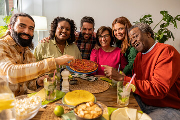 portrait of group of multiracial friends looking at camera inviting to eat pizza at friendly meeting