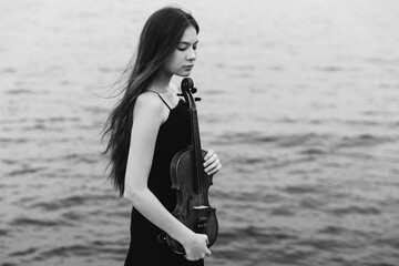 A woman in a black dress holding a violin. Suitable for music or artistic concepts.