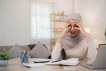 A young Muslim business woman is stressed and has a headache from miscalculating business numbers...