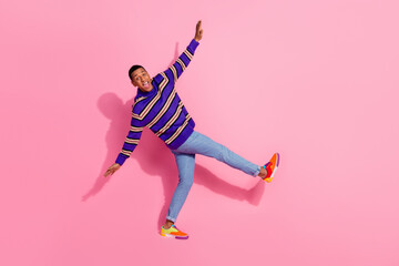 Full length photo of excited funky man wear striped sweater walking dancing isolated pink color...