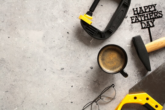 Happy Fathers Day card template. Top view photo of carpentry tools, coffee cup, eyeglasses on stone table.