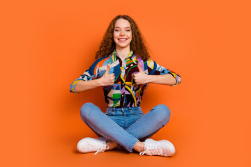 Photo of satisfied cheerful lovely girl wear trendy print clothes thumbs up isolated on vivid orange color background