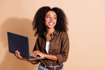 Photo of cheerful girl wear brown blouse look directing hold laptop look at discount empty space...