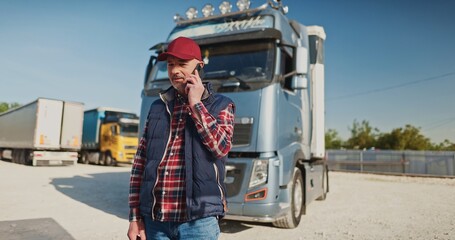 Portrait of male delivery courier man standing and talking by phone outdoors. Professional truck...