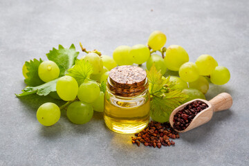 Grape seed oil in small bottle and bunch of grapes together.