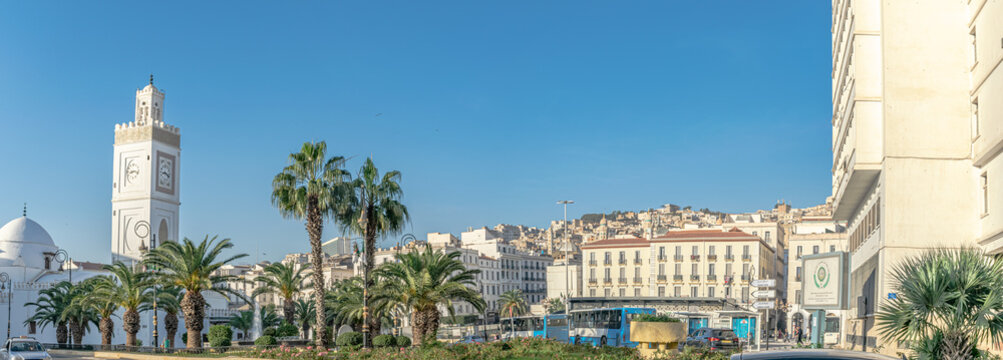 The Martyr's square place in Algiers city. The old great mosque of Algiers. El Hadi Mghiref garden, bus and cars on the road. El Aurassi hotel and palm trees. Algiers, Algeria - October 28, 2022.