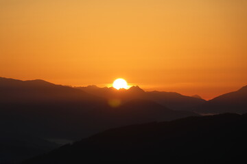 early morning sunrise over a hazy mountain range casting an orange hue in the sky