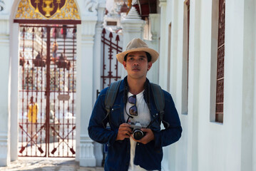 Young Asian traveling backpacker taking photos with camera in Wat Arun in Bangkok, Thailand