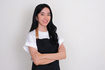 An Asian girl wearing apron smiling confidence at the camera with arms crossed